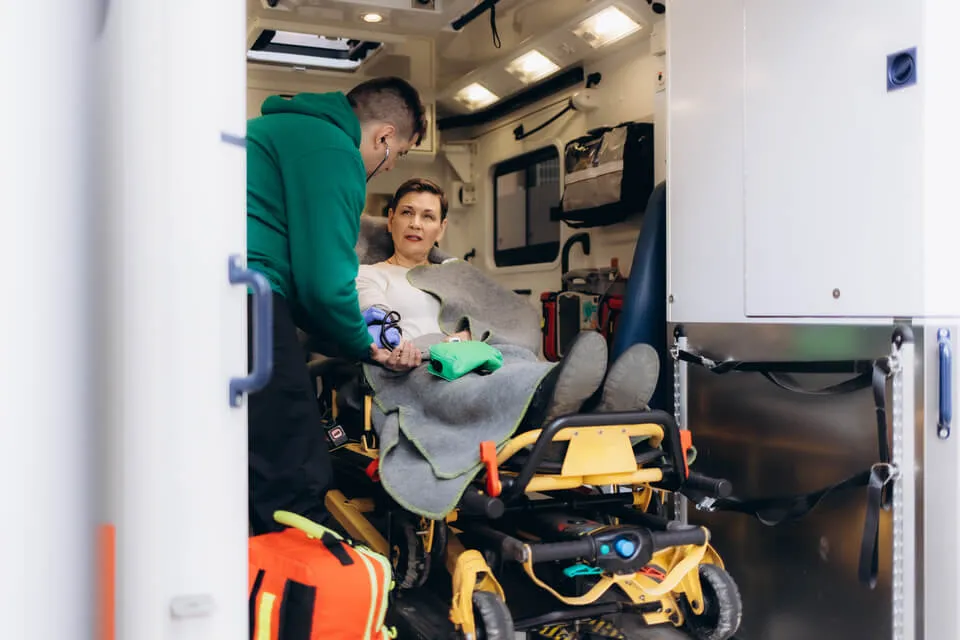 Paziente anziana assistita dal personale durante il trasporto in ambulanza